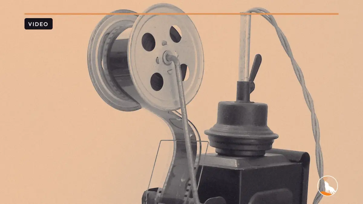 A hand-cranked film projector, graded navy and orange, with the wolf mark.