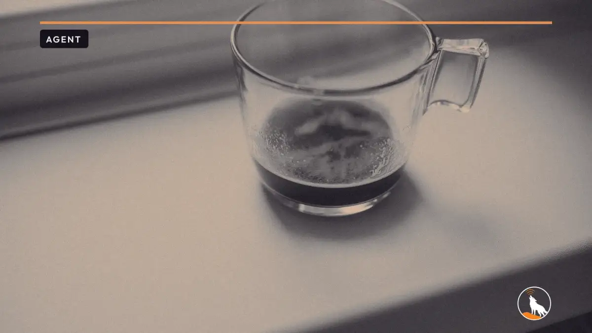 A clear glass cup with a little coffee left in it, sitting on a white window sill in soft morning light.