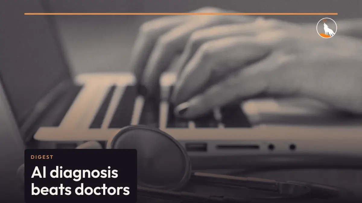 A stethoscope lying on a wooden desk in front of a laptop as a person types.