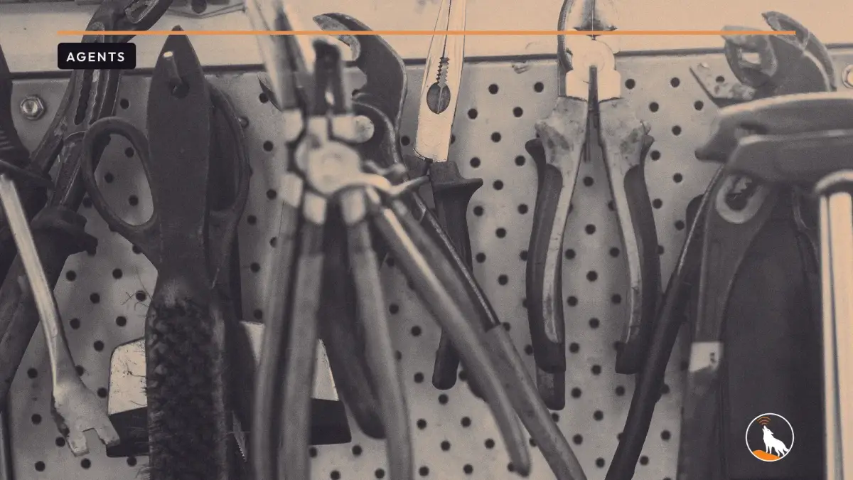 Worn pliers, wrenches, scissors and a wire brush hanging side by side on a perforated pegboard in a workshop.